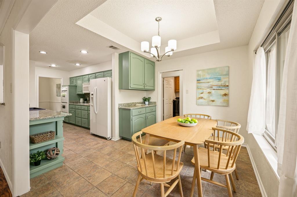 Kitchen featuring green cabinetry, stone-finish countertops, recessed lighting, a tray ceiling, and tile flooring