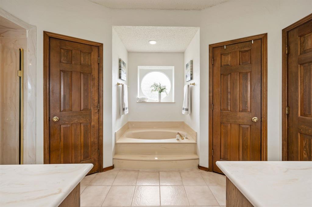 Primary Spa-Style Master Bath featuring dual vanities with marble-finish countertops, wood-finish flooring, and recessed ceiling lighting