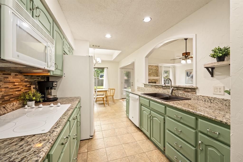 Kitchen featuring sage green cabinetry, stone-patterned countertops, a tiled backsplash, a double-basin sink with a pull-down faucet, and recessed lighting