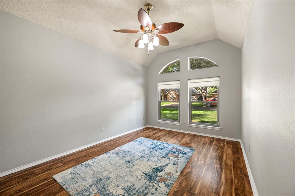 Bedoom featuring vaulted ceilings, wood-finish flooring, dual windows topped with arched clerestory windows, and a multi-light ceiling fan