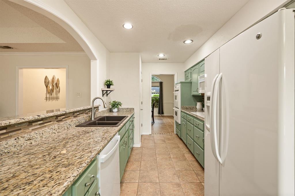 Kitchen featuring stone-finish countertops, dual-basin undermount sink, ceramic tile flooring, recessed lighting, and built-in double wall ovens