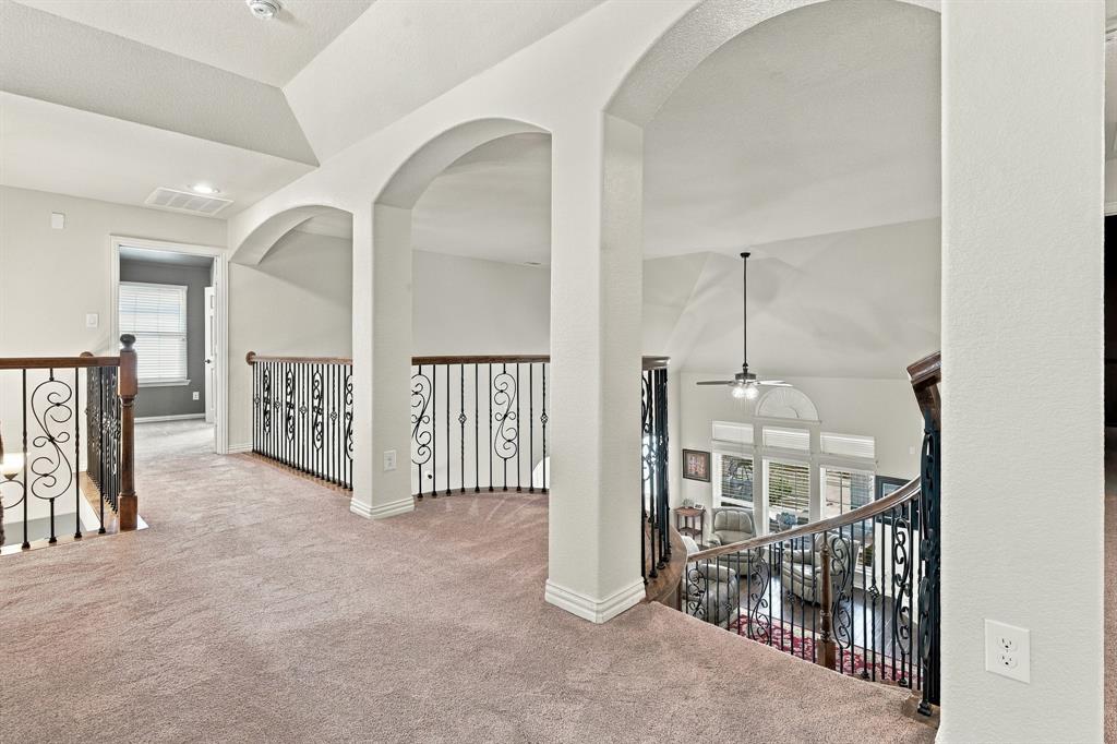 Elevated landing area featuring vaulted ceilings, decorative archways, and ornate metal stair railings