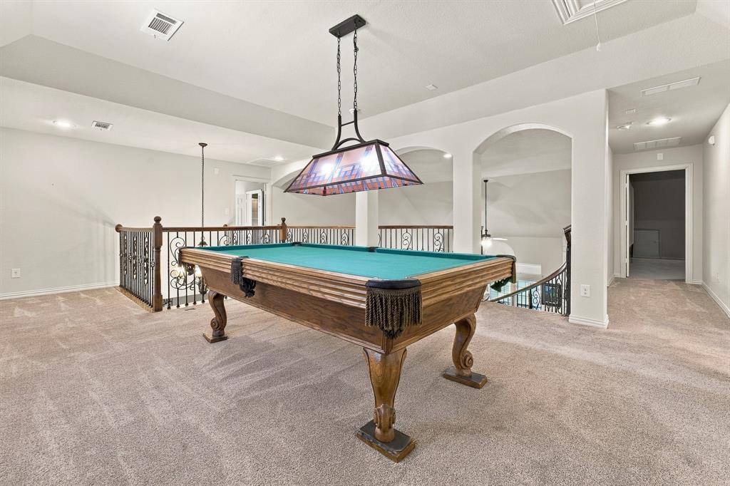 Open floor plan featuring arched architectural pass-throughs, custom wrought-iron railings, tray ceilings, and recessed lighting