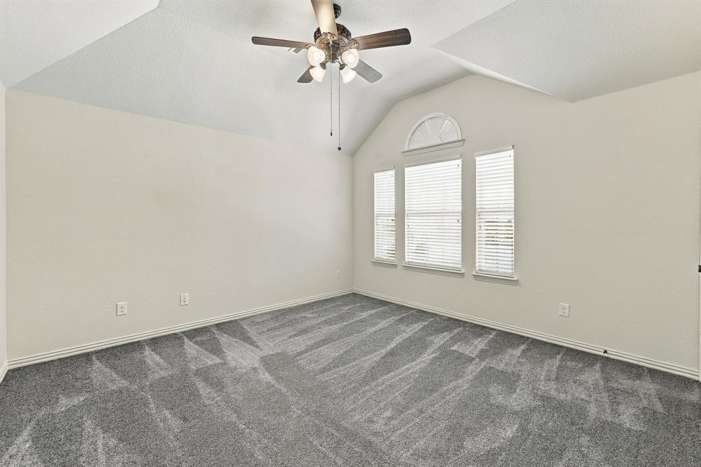 Vaulted ceilings, neutral wall color, wall-to-wall carpeting, ceiling fan with light kit, and multi-pane windows with arched transom detail