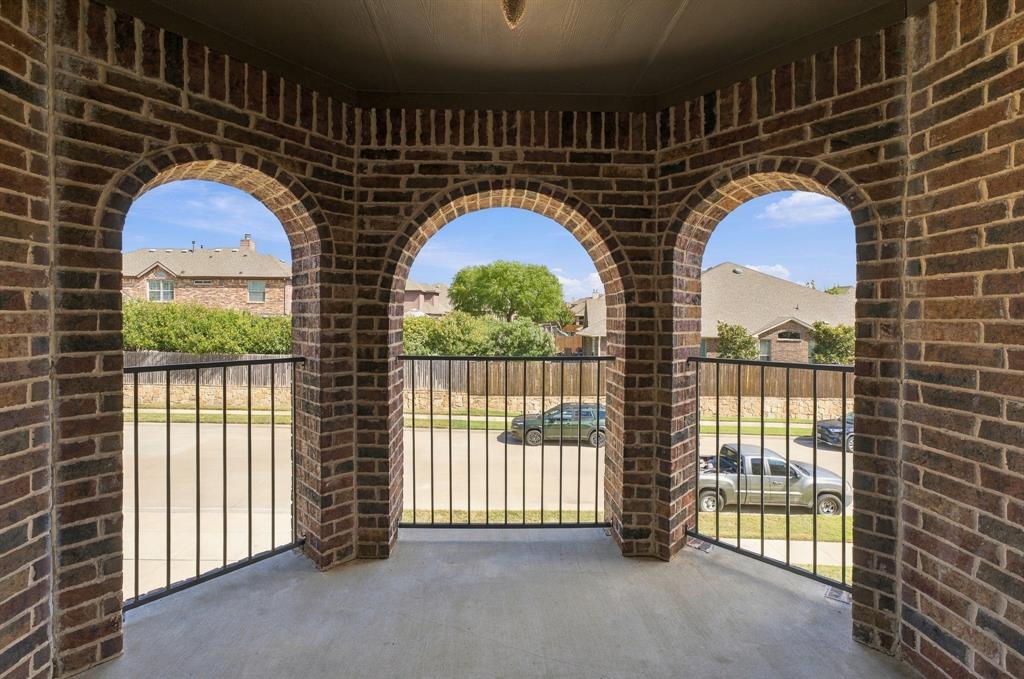 Covered balcony featuring multi-tonal brick masonry, three arched openings, and black metal railings