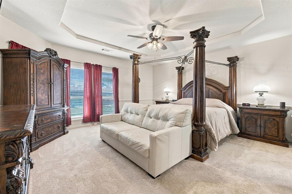 Room featuring an octagonal tray ceiling, neutral wall-to-wall carpeting, and a ceiling fan with integrated lighting