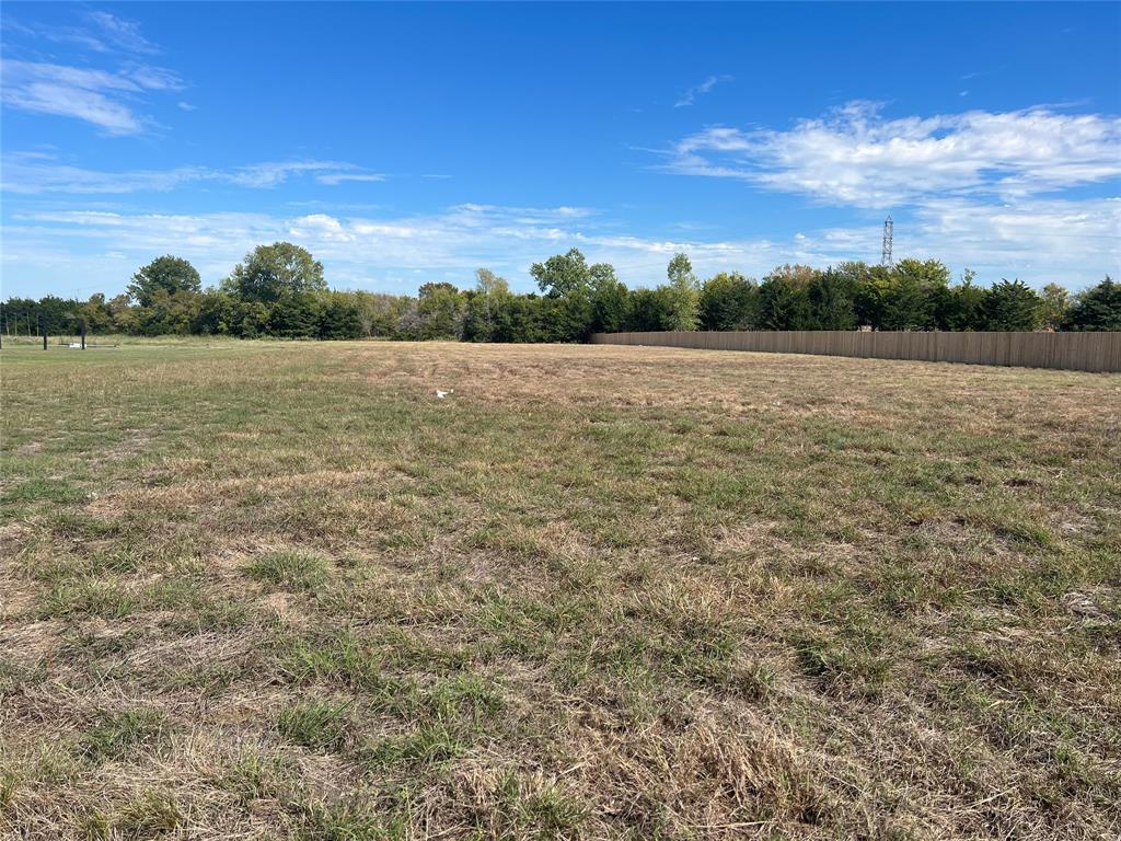 Expansive level lot featuring cleared acreage, perimeter wood fencing, and mature trees