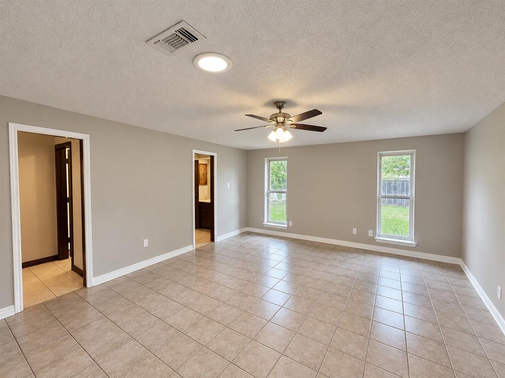 Neutral interior featuring tile flooring, dual double-hung windows, and a ceiling fan with integrated lighting Neutral interior featuring tile flooring, dual double-hung windows, and a ceiling fan with integrated lighting