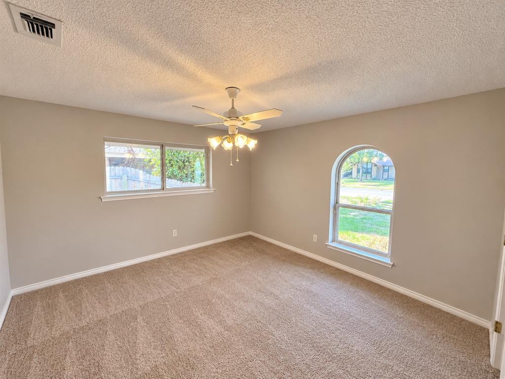 Neutral-toned interior featuring wall-to-wall carpeting, a multi-light ceiling fan, a rectangular window, and an arched window Neutral-toned interior featuring wall-to-wall carpeting, a multi-light ceiling fan, a rectangular window, and an arched window