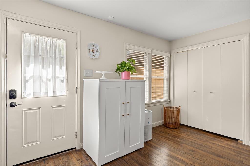 Neutral-toned interior featuring wood-finish flooring, bi-fold closet doors, and multi-pane windows with horizontal blinds