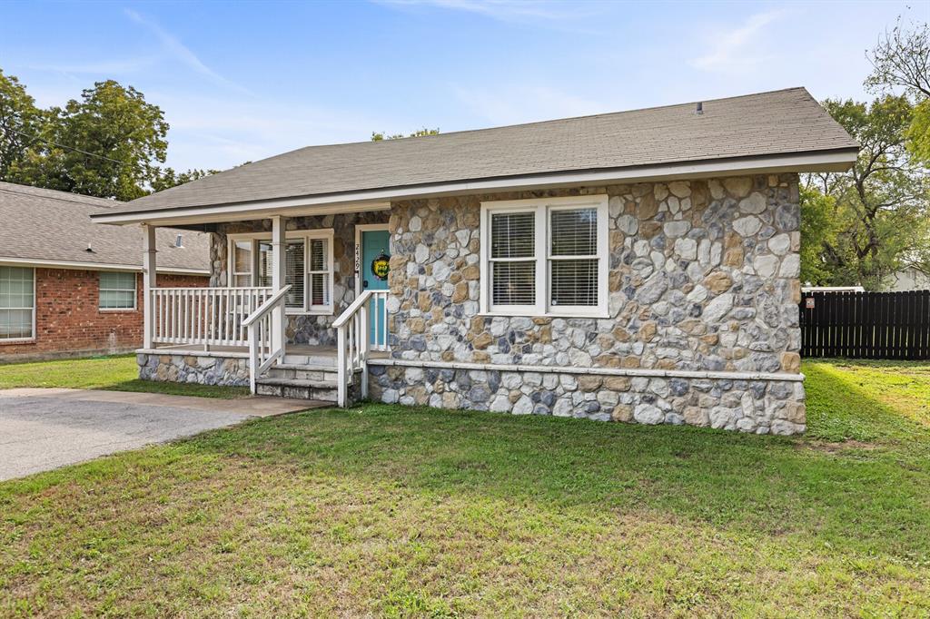 Stone veneer exterior featuring a covered front porch with white railing, asphalt shingle roof, and multi-pane windows