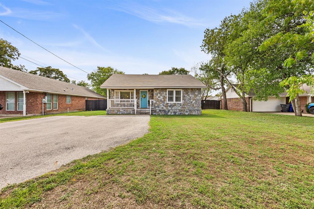 Exterior facade featuring stone veneer, a covered front porch with white railing, and an expansive front lawn