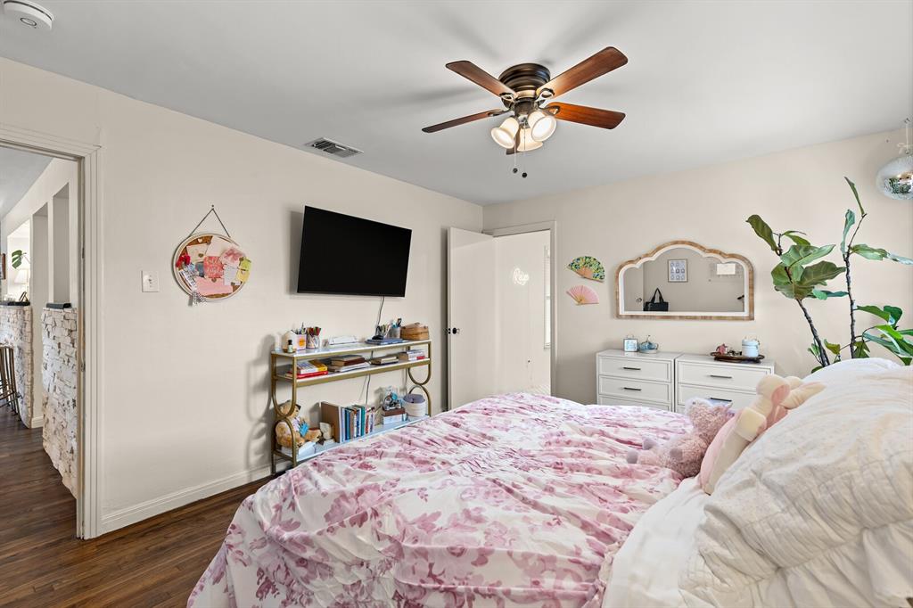 Room interior featuring wood-finish flooring, a multi-blade ceiling fan with integrated light fixture, and neutral wall color
