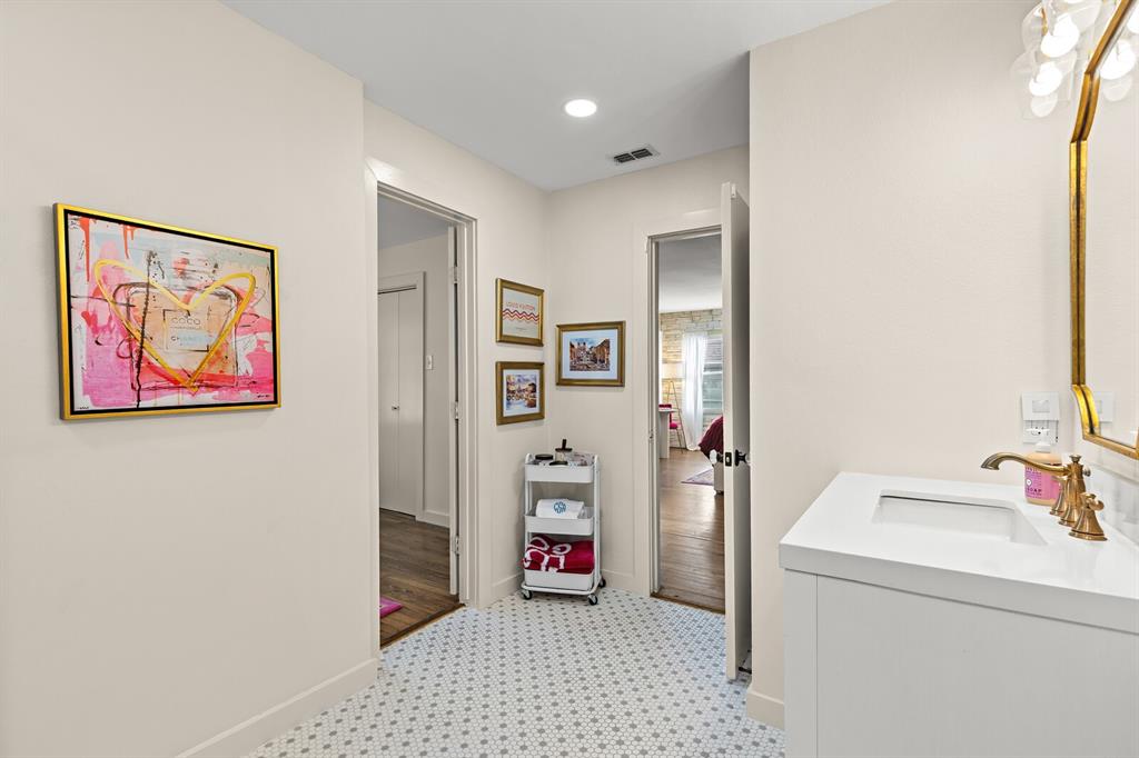 Bathroom featuring a vanity with a rectangular sink, brass-tone faucet, geometric hexagonal tile flooring, and a decorative gold-framed wall mirror