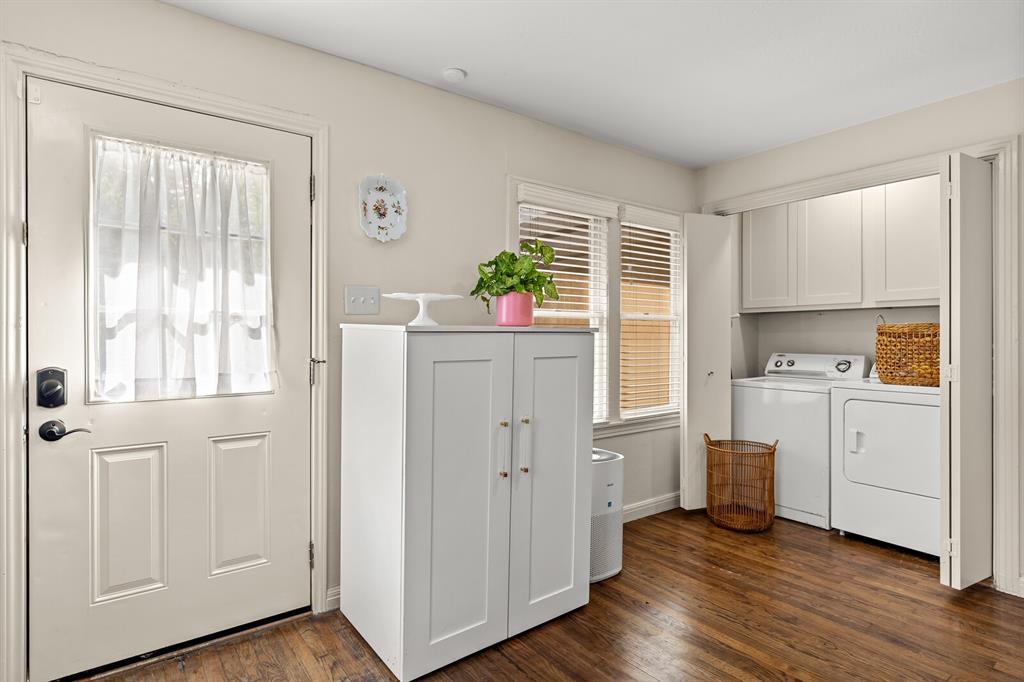 Laundry area featuring wood-finish flooring, white upper cabinetry, and dual bifold doors