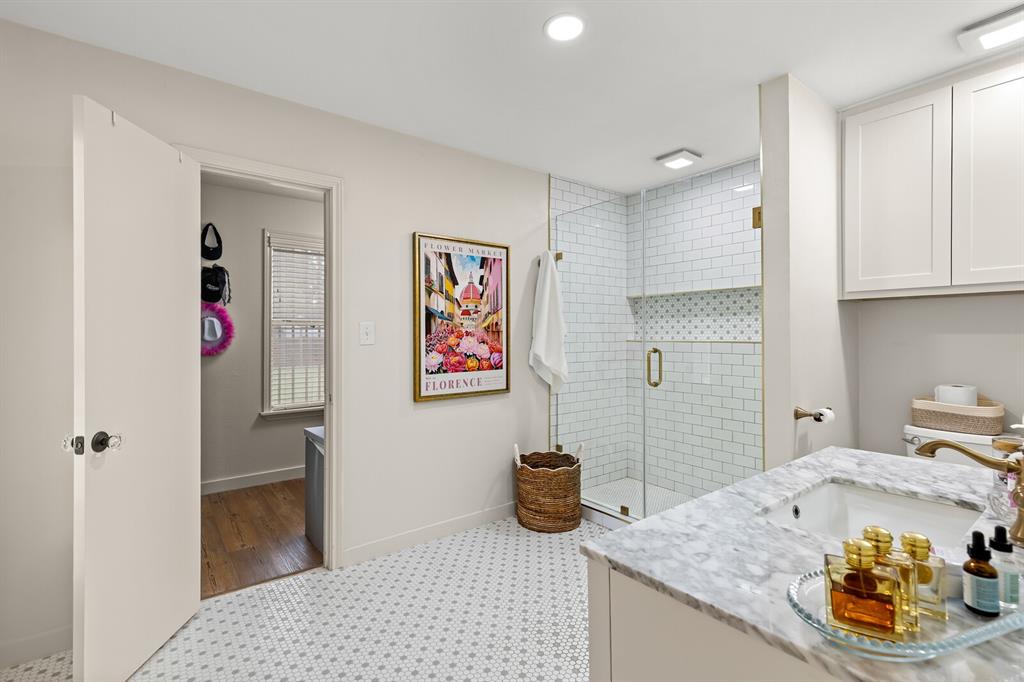 Bathroom featuring a stone-surface vanity with an integrated sink, shower enclosure with white subway tile surround, patterned mosaic floor tile, and shaker-style cabinetry