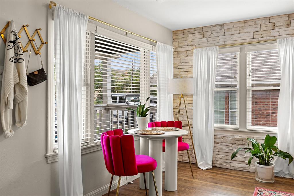 Stacked stone accent wall with wood-finish flooring and multiple windows featuring horizontal blinds