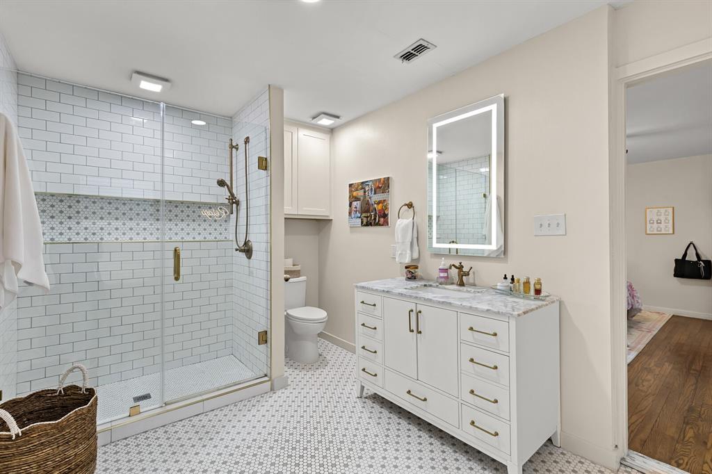 Walk-in shower with white subway tile surround, integrated mosaic accent niche, and frameless glass door