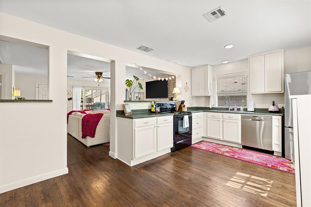 Kitchen featuring white cabinetry, solid-surface countertops, wood-finish flooring, and stainless steel appliances