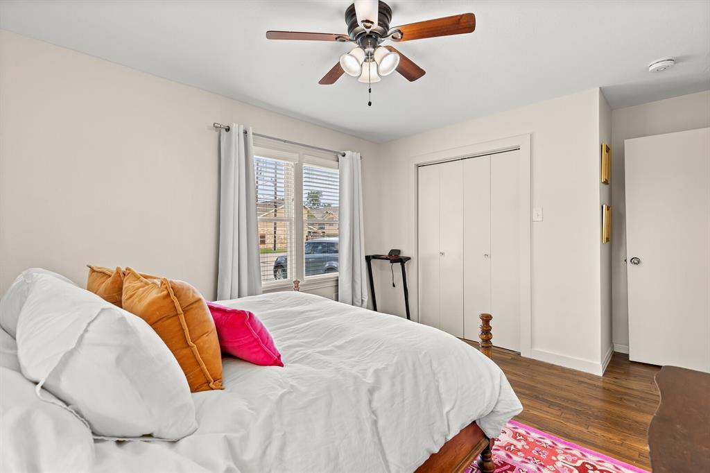 Room featuring wood-finish flooring, a multi-blade ceiling fan with integrated lighting, and a double-door closet