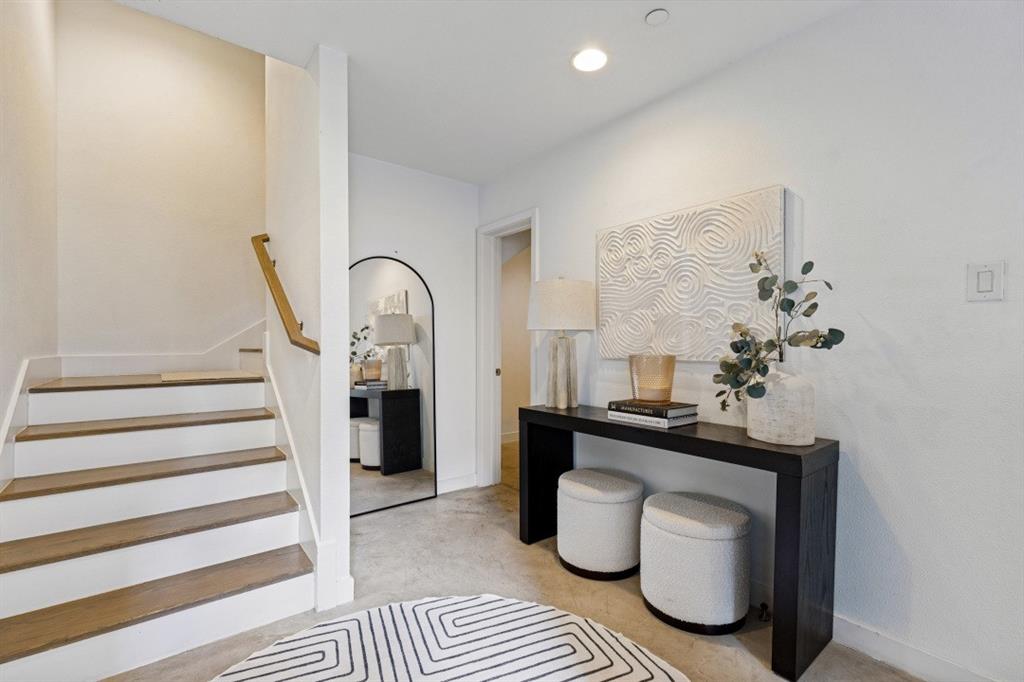 Staircase featuring wood-finish treads and white risers, accompanied by a wall-mounted wooden handrail and recessed lighting