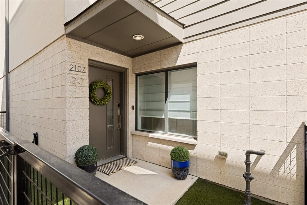 Modern facade featuring split-face block masonry, a covered entryway with recessed lighting, and a metal-framed door with a vertical glass panel