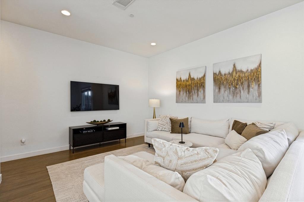Living space featuring wood-finish flooring, crisp white walls, and recessed ceiling lighting
