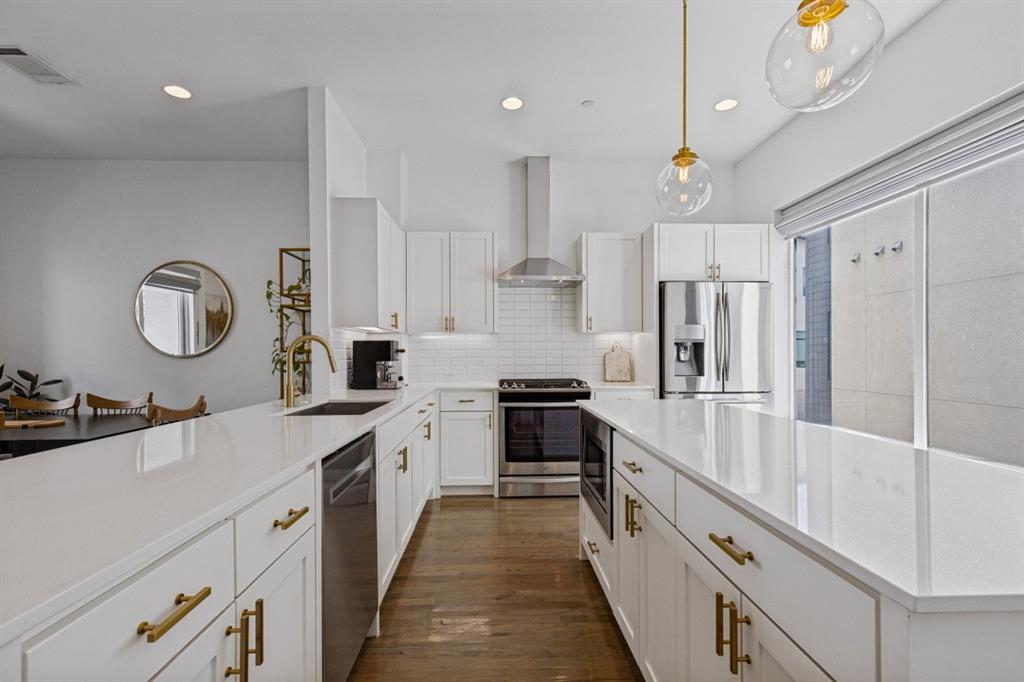 Kitchen featuring white shaker-style cabinetry, solid-surface countertops, wood-finish flooring, a stainless steel range with chimney-style hood, and pendant lighting
