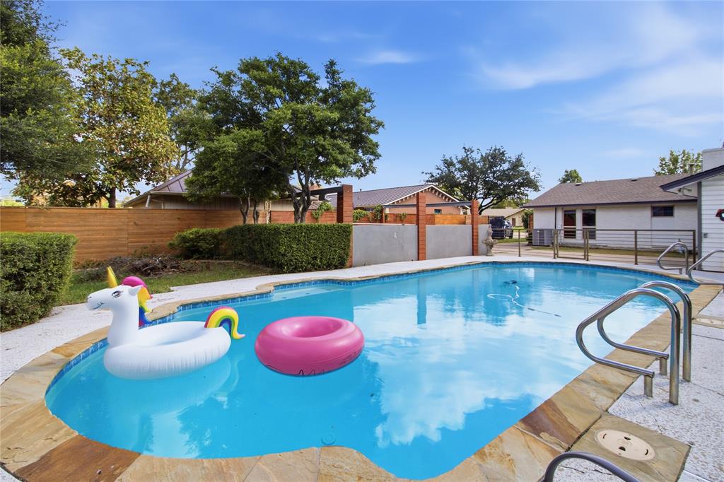 Who’s ready for a pool party? The sparkling swimming pool takes center stage, with colorful floats adding a playful touch to this backyard retreat. Mature trees, neatly trimmed hedges, and attractive wood privacy fencing create a lush, inviting setting. Beyond the pool, an additional grassy area offers even more outdoor space to enjoy, whether relaxing in the sunshine or gathering with friends and family.