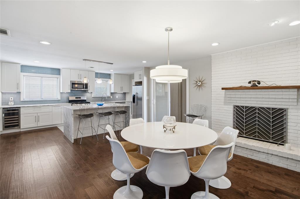 The beautifully appointed kitchen flows effortlessly into the dining area, creating an inviting space for cooking and conversation. A striking waterfall-edge island offers casual seating for three, while crisp white shaker-style cabinetry with soft-close drawers, a blue-gray subway tile backsplash, stainless steel appliances, and a built-in beverage refrigerator combine style with everyday functionality. The open layout keeps the kitchen connected to the dining and living areas, making everything from meal preparation to casual dining feel effortless.