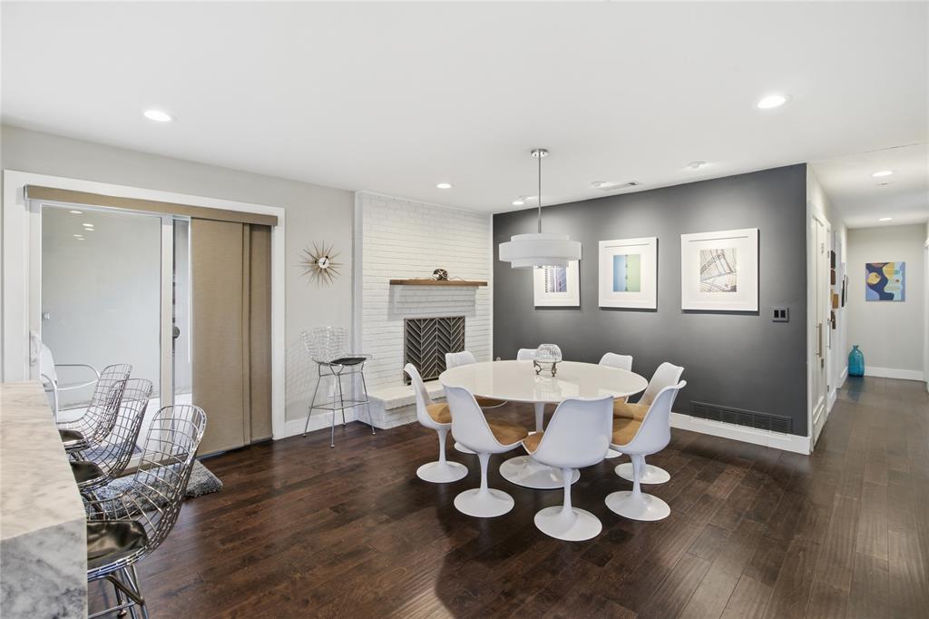 The dining area combines contemporary style with distinctive architectural character. A contrasting charcoal accent wall, modern pendant lighting, and white-painted brick create an inviting atmosphere, while the open layout provides a natural connection to the kitchen. Sliding glass doors bring in natural light and offer convenient outdoor access, making this a welcoming space for everything from everyday meals to entertaining guests.