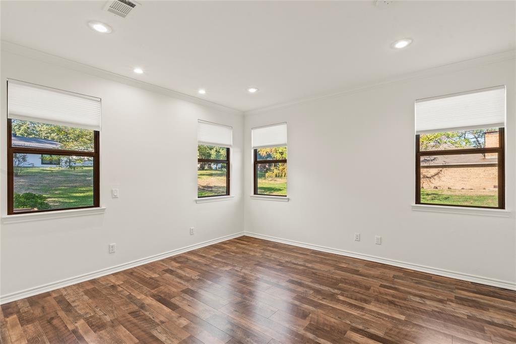 Primary bedroom featuring wood-look flooring, recessed lighting, and multiple windows.