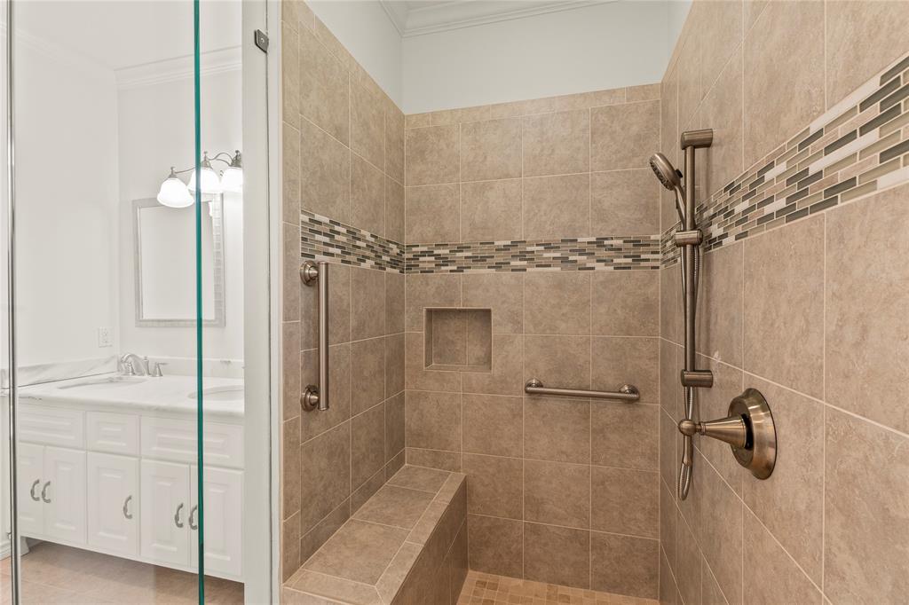 Primary Walk-in tiled shower featuring decorative tile accents, a built-in bench, and handheld showerhead.