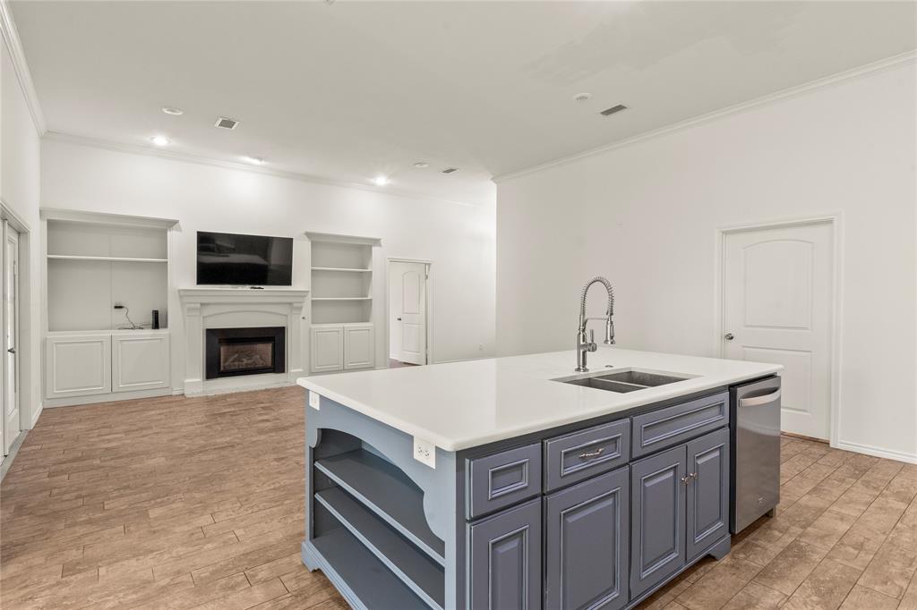 Open-concept kitchen overlooking the living area with a gas fireplace and custom built-in shelving.