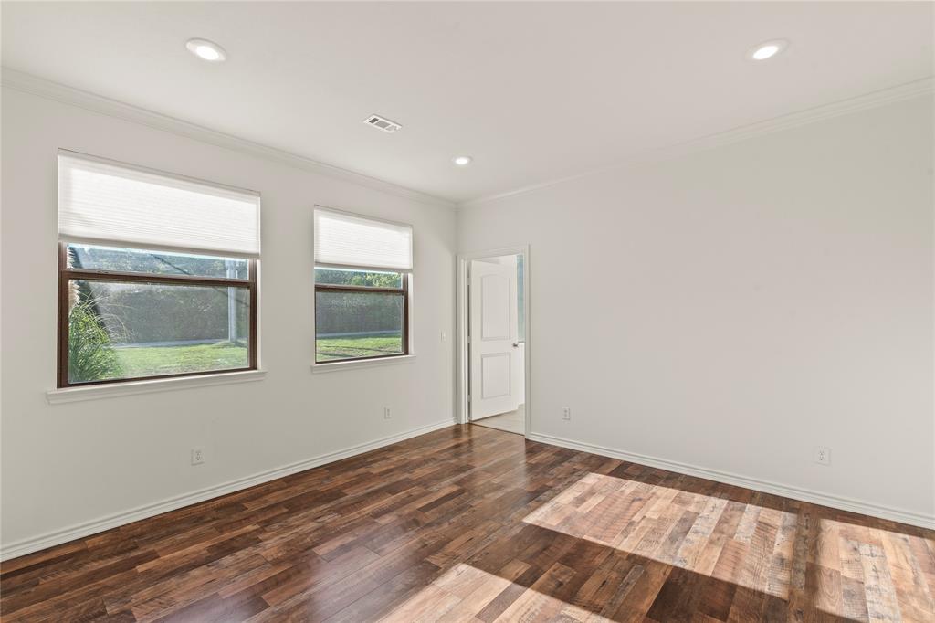 Ensuite bedroom two featuring wood flooring, recessed lighting, and large windows overlooking the backyard.