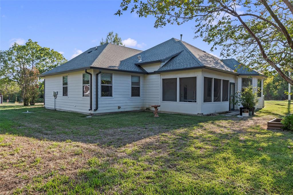Rear exterior view of the home featuring an screened in back patio and part of the spacious backyard.