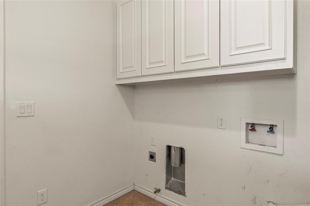 Laundry room with washer and dryer connections and overhead cabinetry.