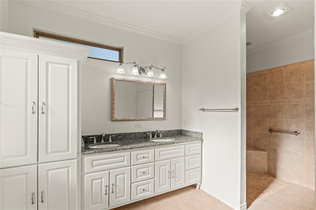 Ensuite bathroom two with double-sink granite vanity, generous cabinet storage, and walk-in tiled shower.