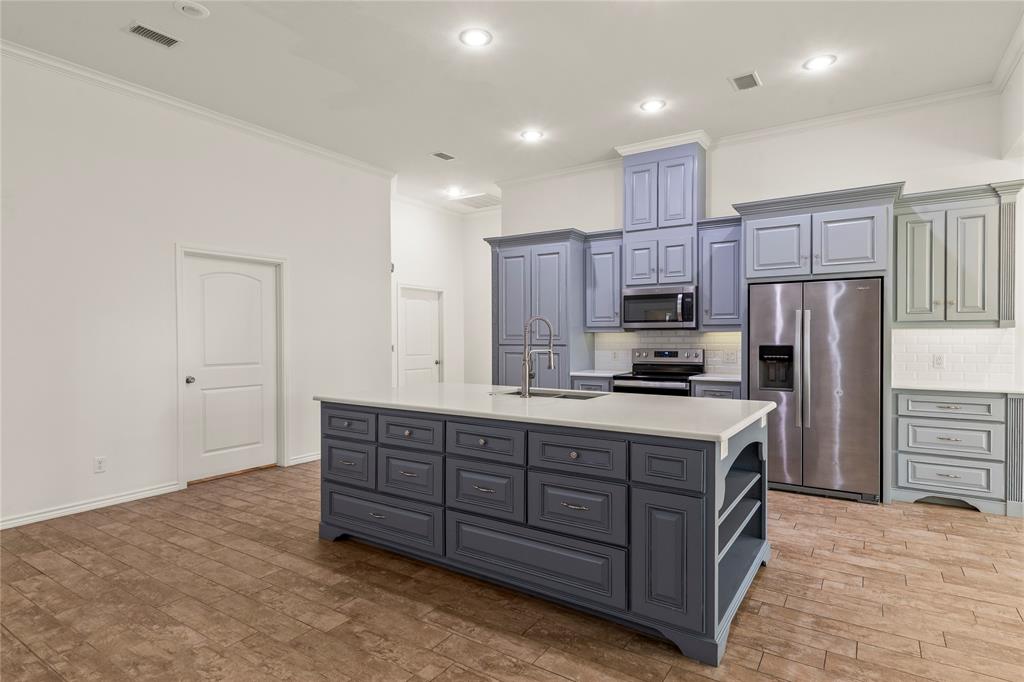 Large kitchen island offering generous countertop space, storage drawers, and additional open shelving.