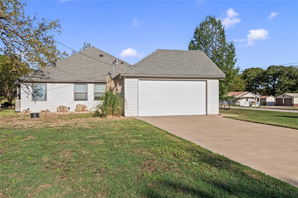 Side exterior showcasing the attached two-car garage and concrete driveway.