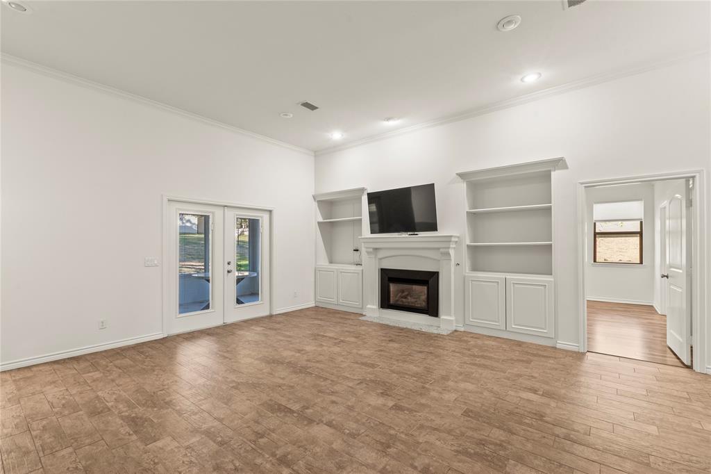 Living room featuring a fireplace, custom built-in shelving, and French doors opening to the screened porch.