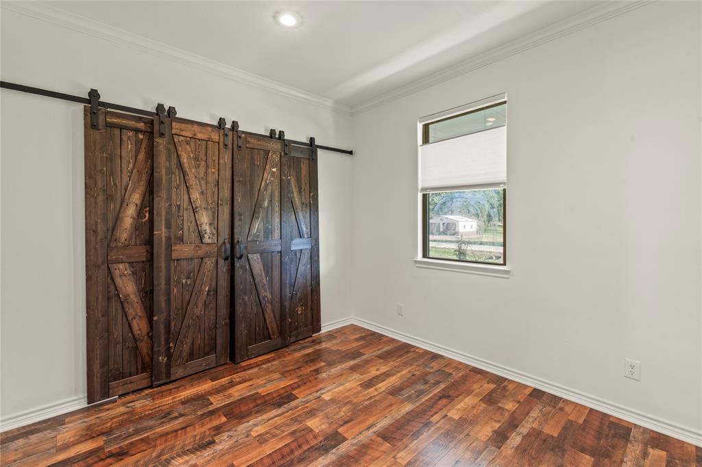 Ensuite Bedroom One featuring wood-look flooring, natural light, and rustic sliding barn doors to closet.