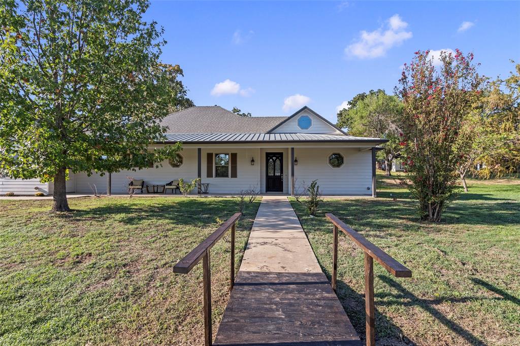 Welcoming front exterior with a covered front porch and mature shade trees.