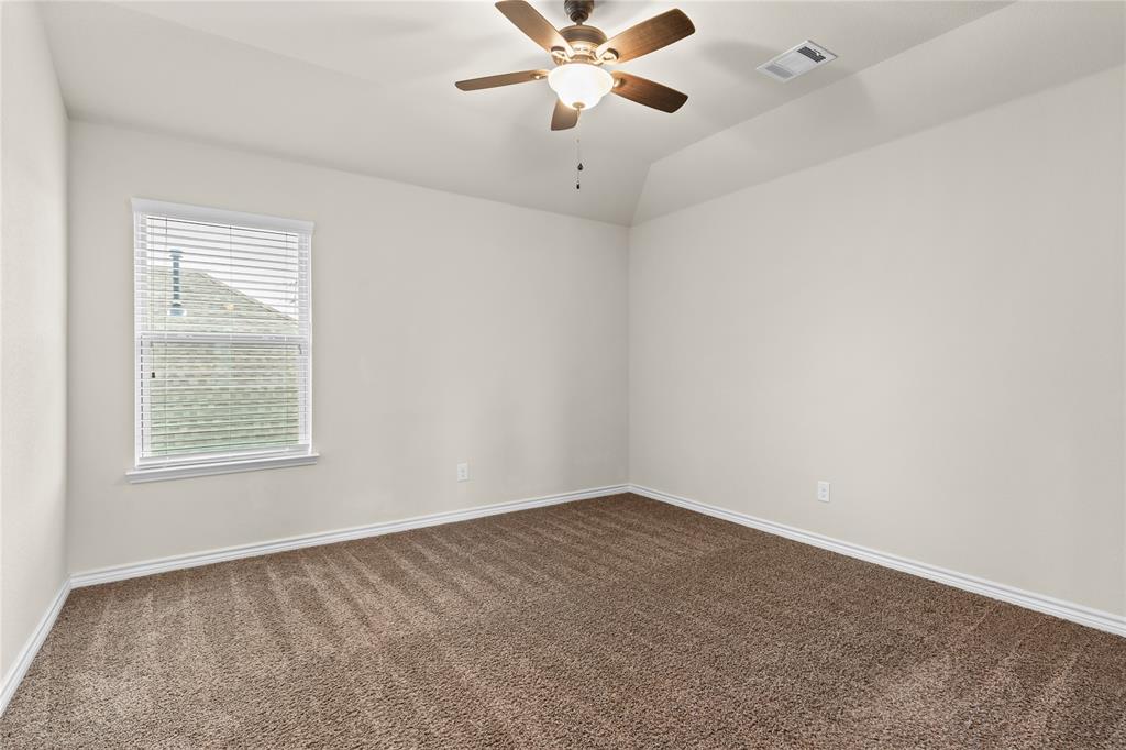 Interior space featuring vaulted ceilings, neutral wall tones, textured carpeting, and a ceiling fan with integrated lighting