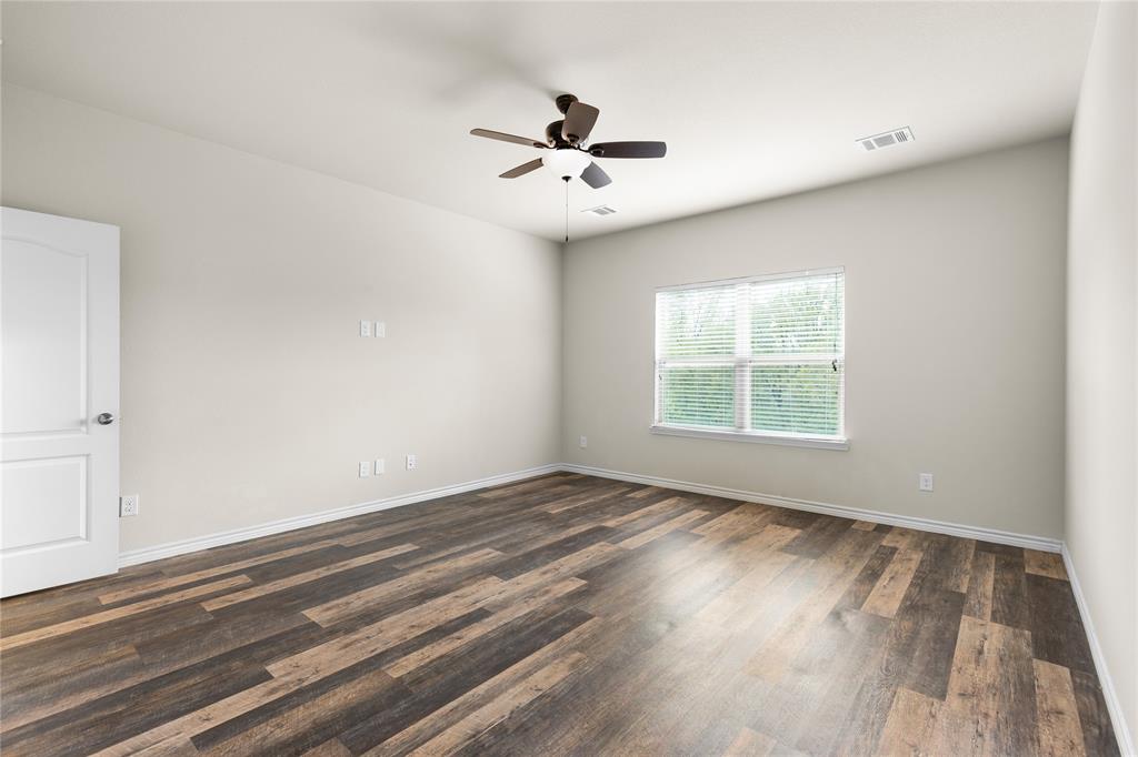 Wood-finish flooring, neutral wall tones, multi-pane window, and ceiling fan with integrated lighting