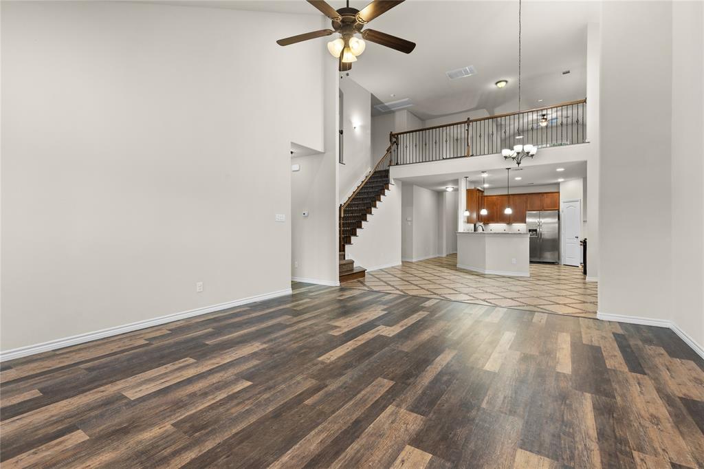 Vaulted ceilings, wood-finish flooring, built-in staircase with metal balusters, and a mezzanine overlook with iron railing