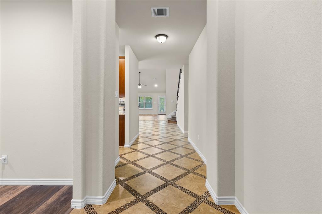 Entryway featuring stone-tile flooring with decorative mosaic inlay, neutral wall paint, and recessed lighting