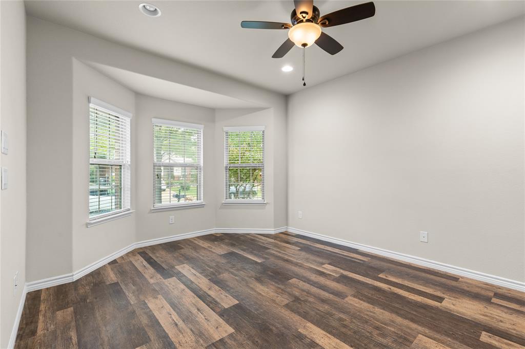 Bay window featuring multi-pane glass, wood-finish flooring, ceiling fan with integrated lighting, and neutral wall tones