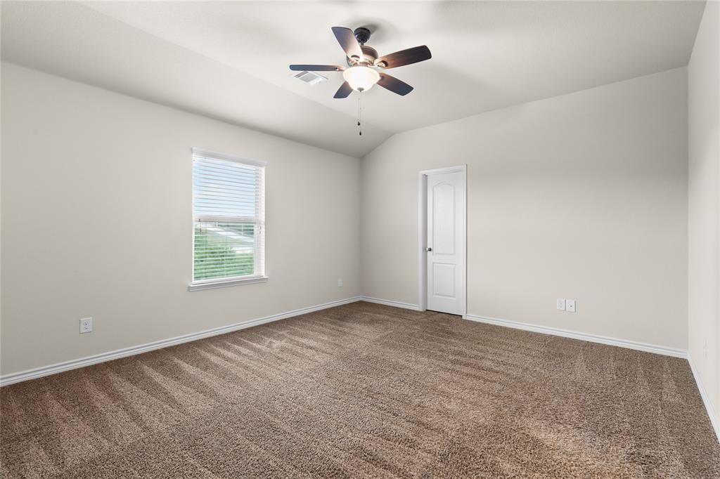 Neutral-toned room featuring vaulted ceilings, carpeting, a ceiling fan with integrated lighting, and a single-panel interior door