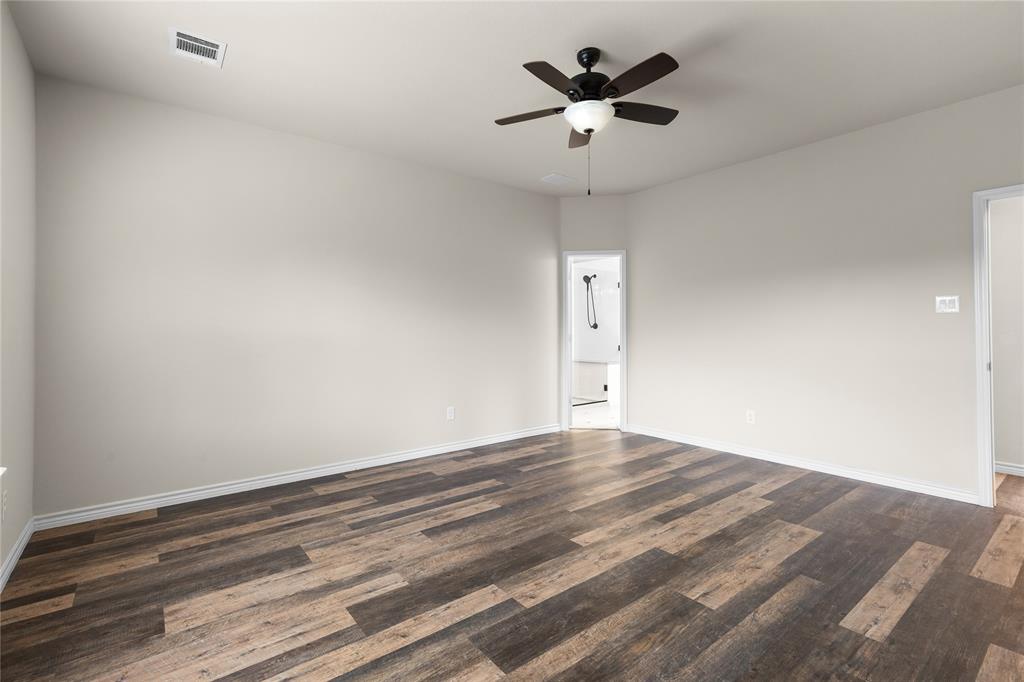 Spacious room featuring wood-finish flooring, neutral wall paint, and a ceiling-mounted fan with integrated lighting